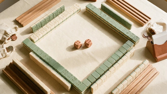 Overhead view of a partially set up American Mahjong game with four tile walls arranged in a square on a linen table, with wooden dice at the center.