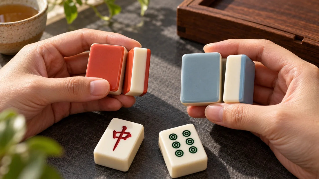 Hands comparing coral and pale blue tile backs beside a red dragon and a six-dot tile.