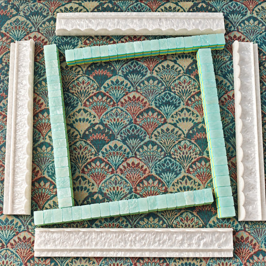 Four white BamChive pearlescent acrylic mahjong racks and pushers arranged around aqua display tiles on a patterned mat.