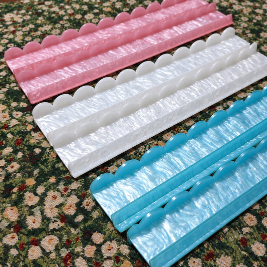Pink, white and blue BamChive pearlescent acrylic mahjong racks and pushers showing their scalloped edges and pearl finish.