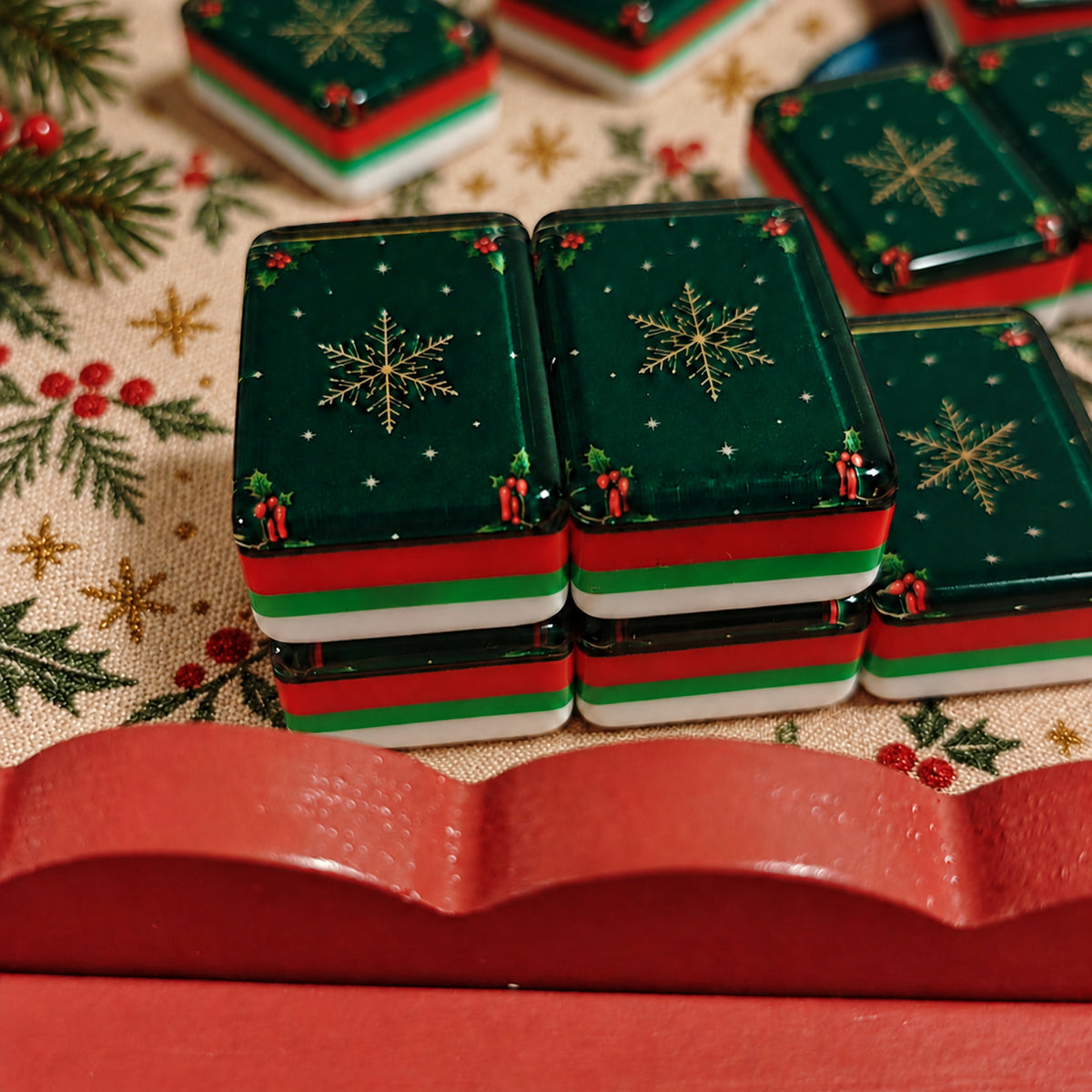 BamChive Green Christmas Star mahjong tile backs with red, green and white layered edges on a Christmas holly-patterned tablecloth.