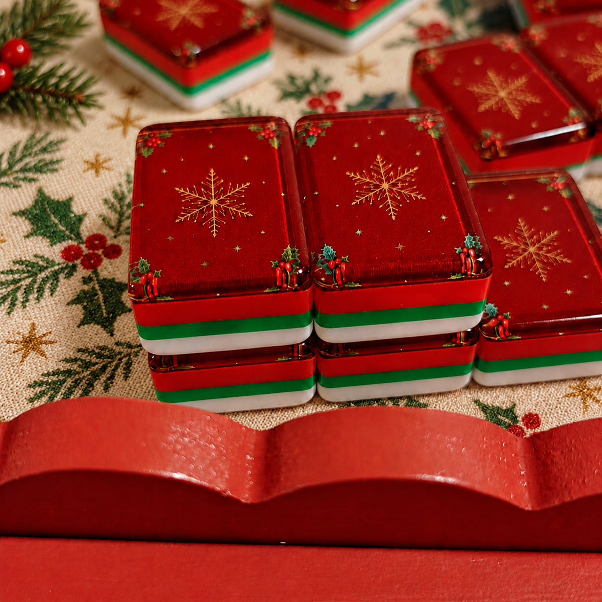 BamChive Red Christmas Star mahjong tile backs with red, green and white layered edges on a Christmas holly-patterned tablecloth.