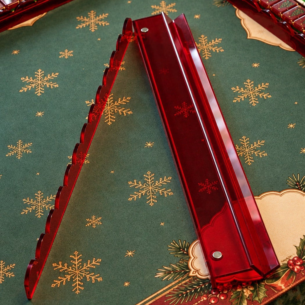 Ruby red acrylic mahjong rack and pusher displayed on a Christmas mat with matching mahjong tiles in the background.